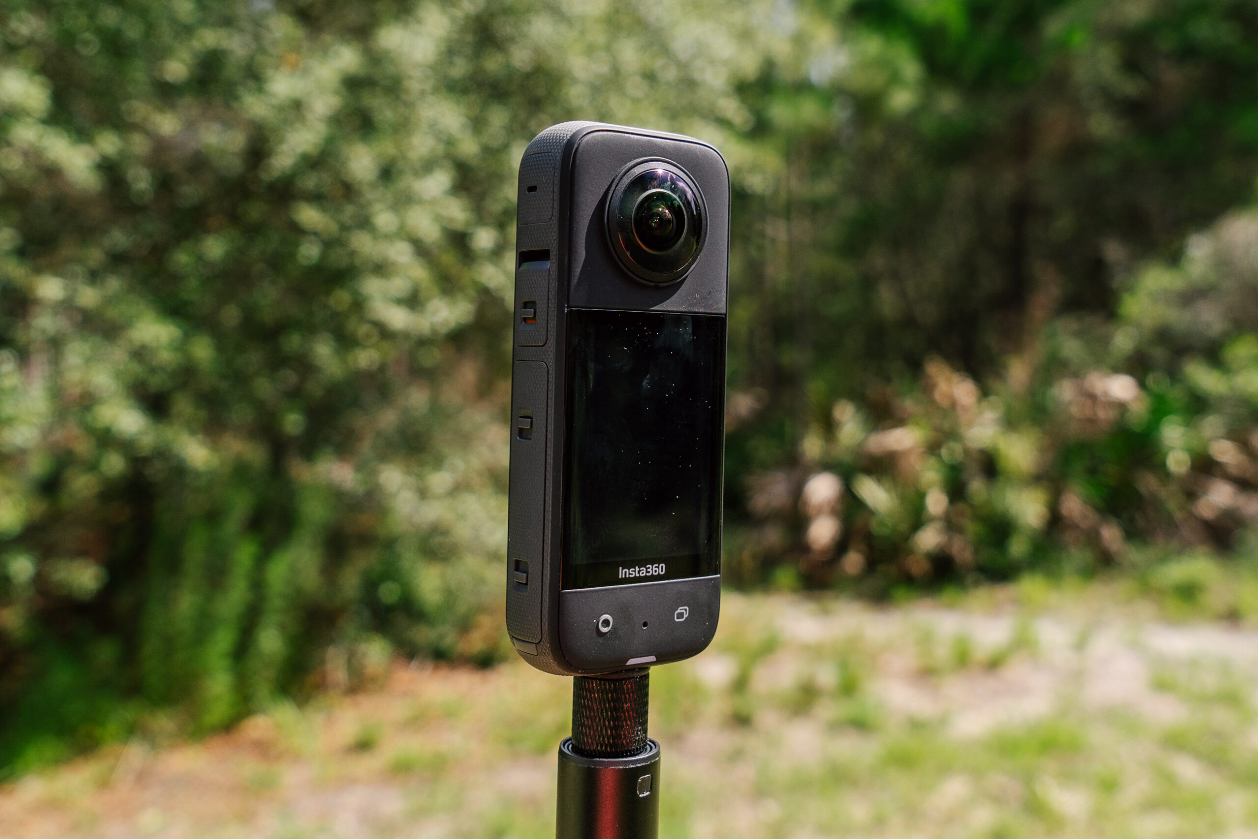 Insta360 X3 action camera with a forest in the background